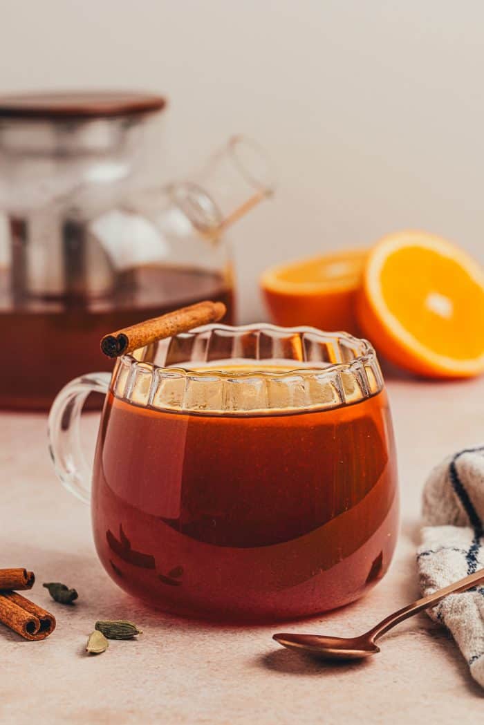 A glass mug filled with chai vanilla bean hot toddy and garnished with orange slices. 
