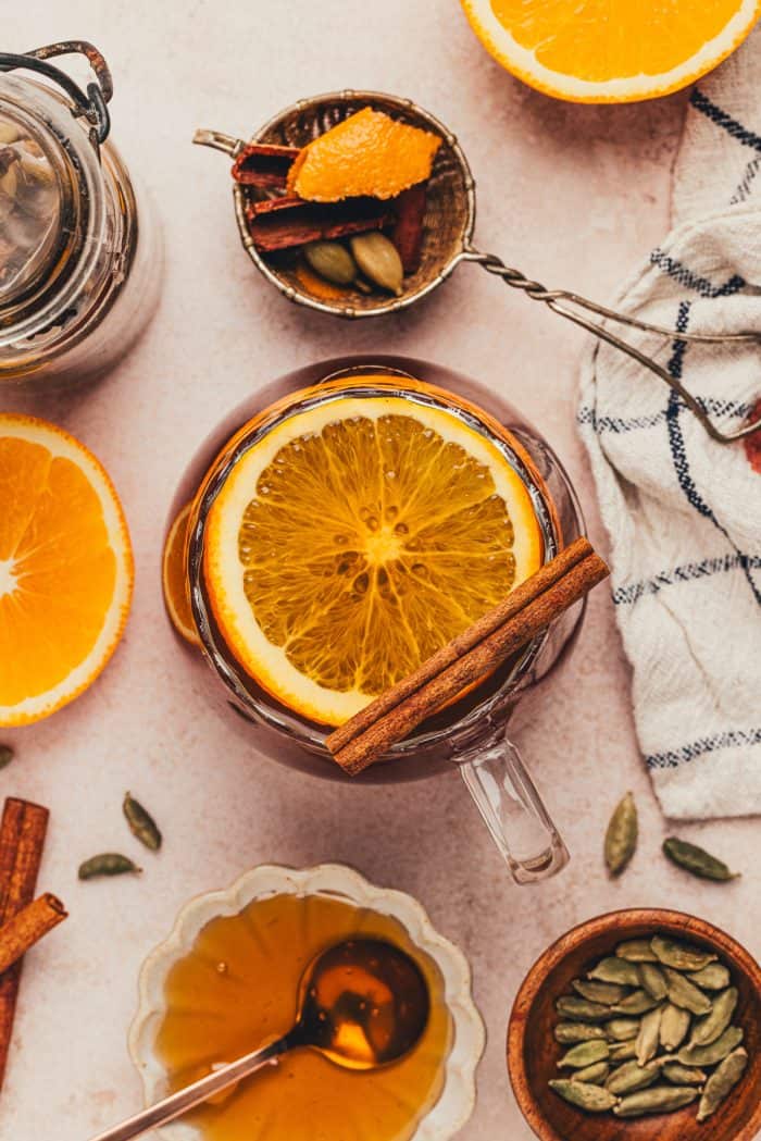 A glass mug filled with chai vanilla bean hot toddy and garnished with orange slices.