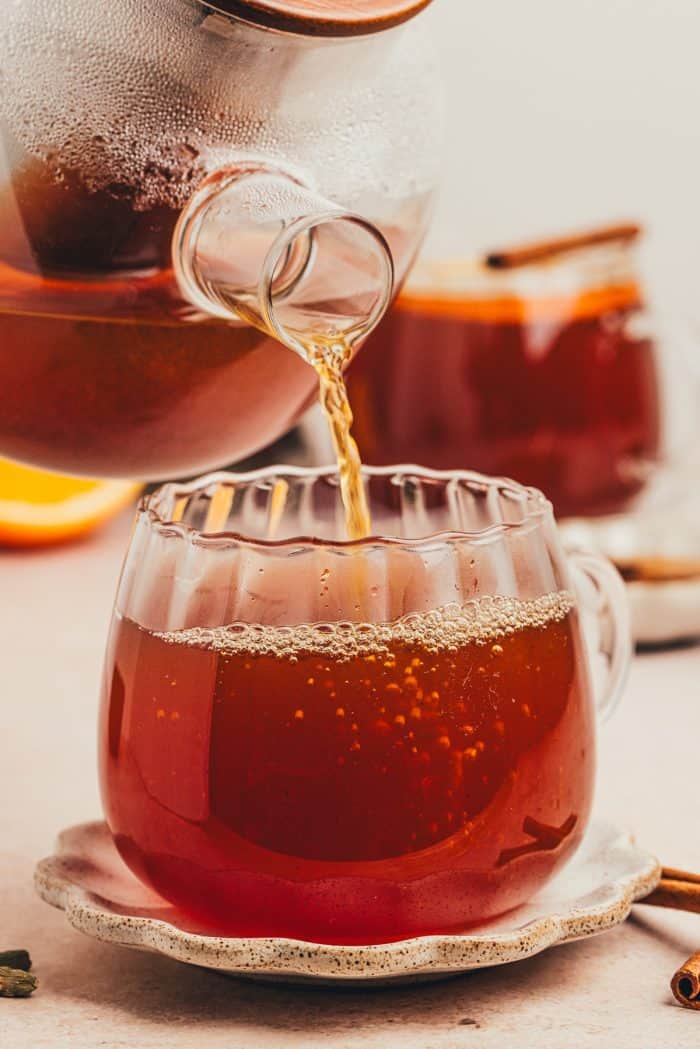 The hot toddy being poured into a glass mug. 