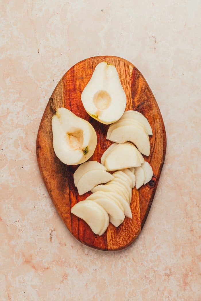 Thinly sliced pears on a wooden cutting board. 