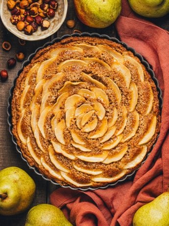 An overhead view of the pear frangipane tart with a red napkin wrapped around it.