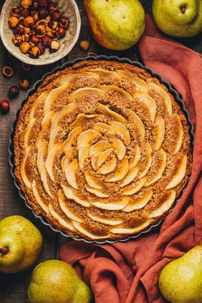 An overhead view of the pear frangipane tart with a red napkin wrapped around it. 