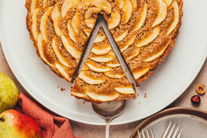 An overhead view of the pear frangipane tart with a slice being removed. 