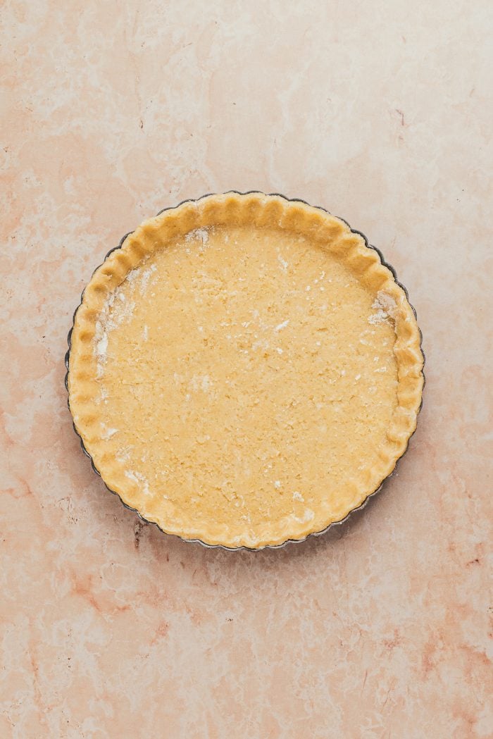 The unbaked tart shell dough in a tart pan.