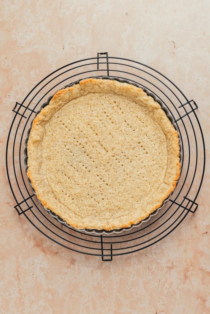 A baked tart shell cooling on a cooling rack.