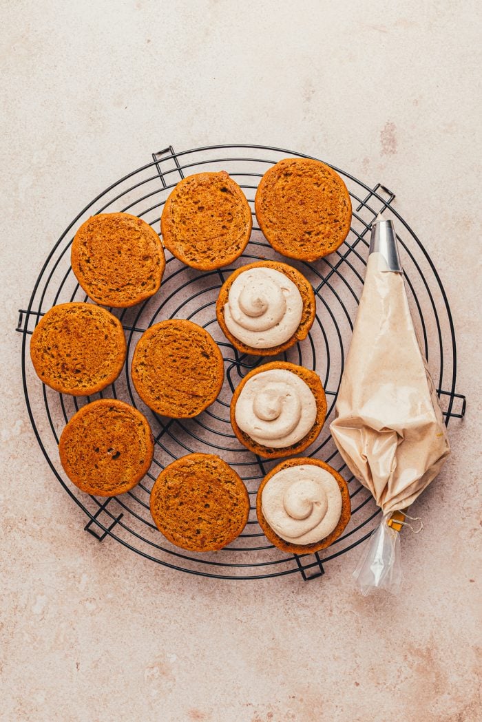Piped cinnamon cream cheese on baked pumpkin whoopie pies halves. 