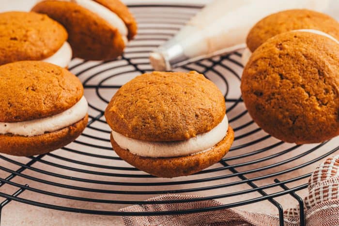 Pumpkin whoopie pies on a round cooling rack. 