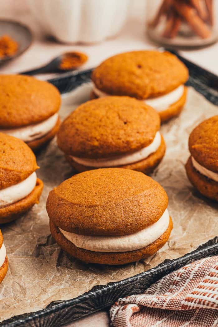 A variety of pumpkin spice whoopie pies on a tray.