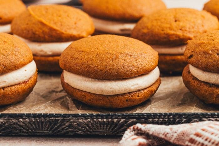 A variety of pumpkin spice whoopie pies on a tray.