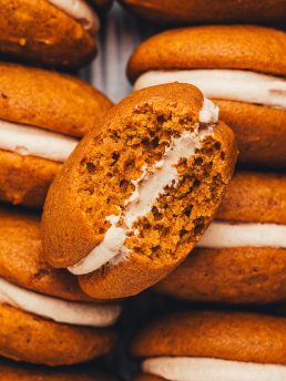 An up close picture of a pumpkin whoopie pies with a bite taken out of it.