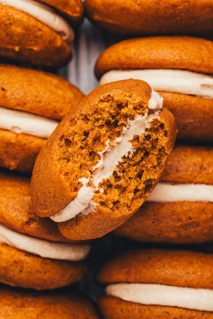 An up close picture of a pumpkin whoopie pies with a bite taken out of it.