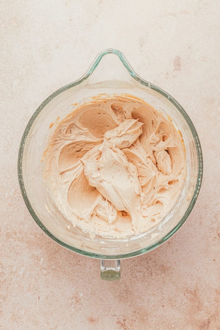 A glass mixing bowl with cream cheese and cinnamon.