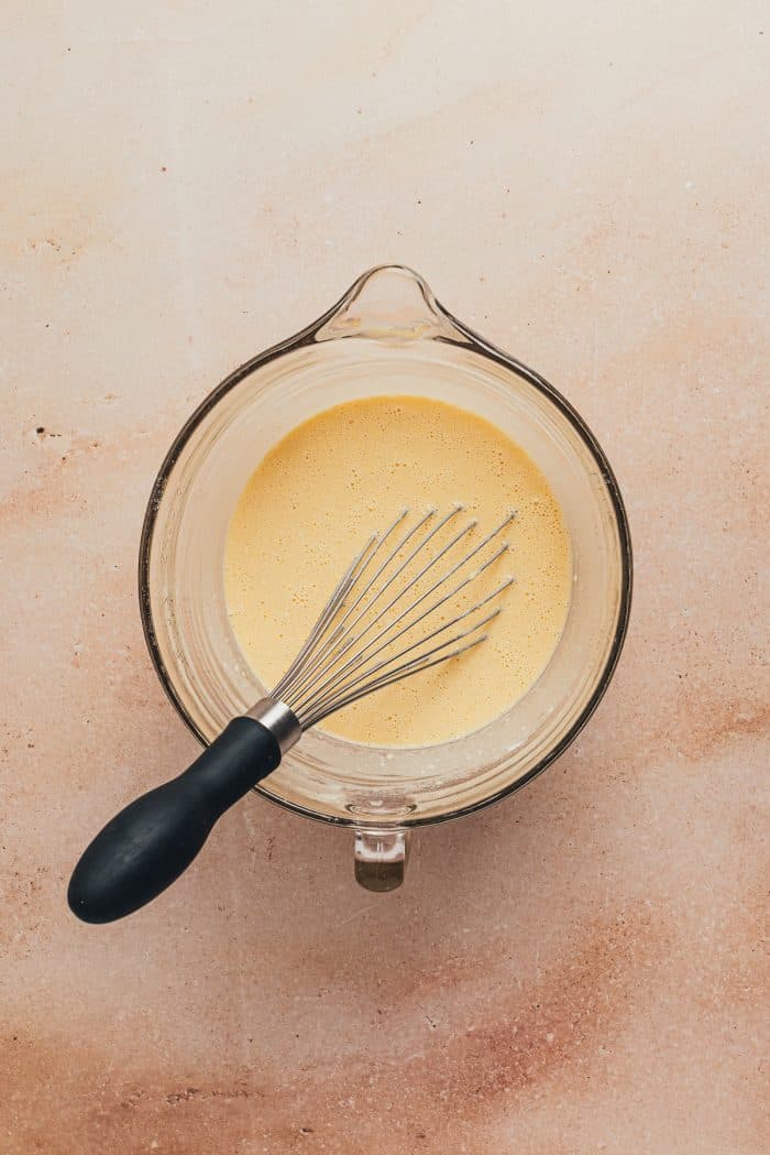 The popover batter in a large sprouted mixing bowl with a whisk.