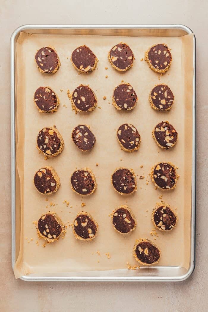 The sliced unbaked chocolate slice and bake cookies on a parchment paper lined baking sheet.