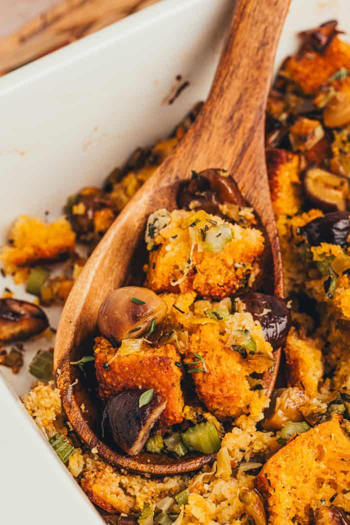 A spoonful of stuffing being lifted out of the baking dish.