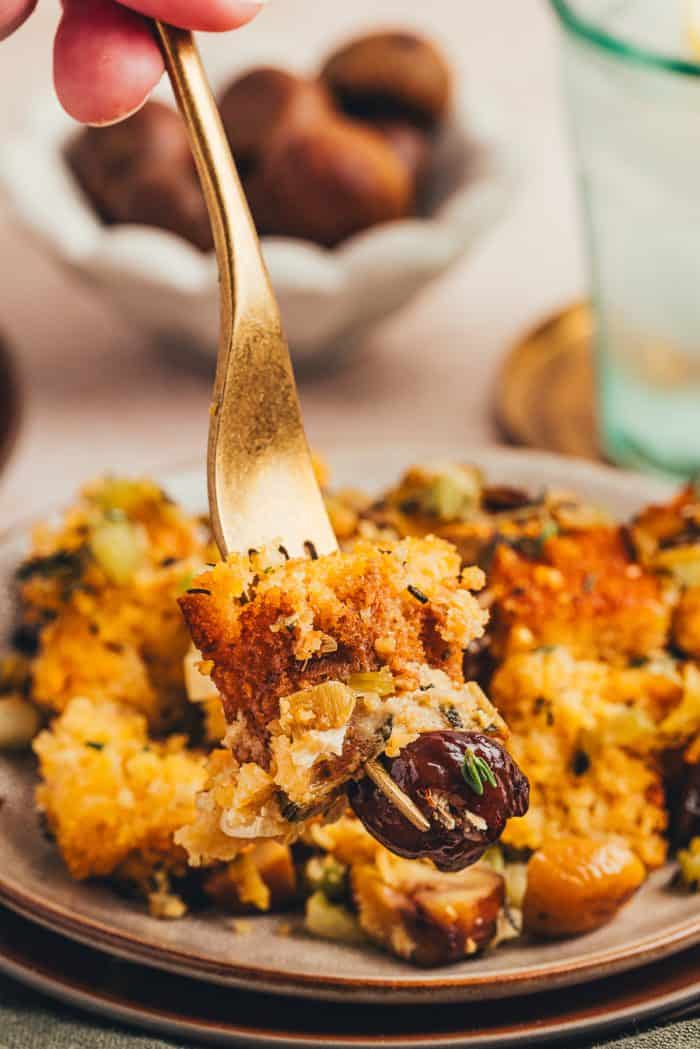 A fork being placed into a small plate of cornbread stuffing.