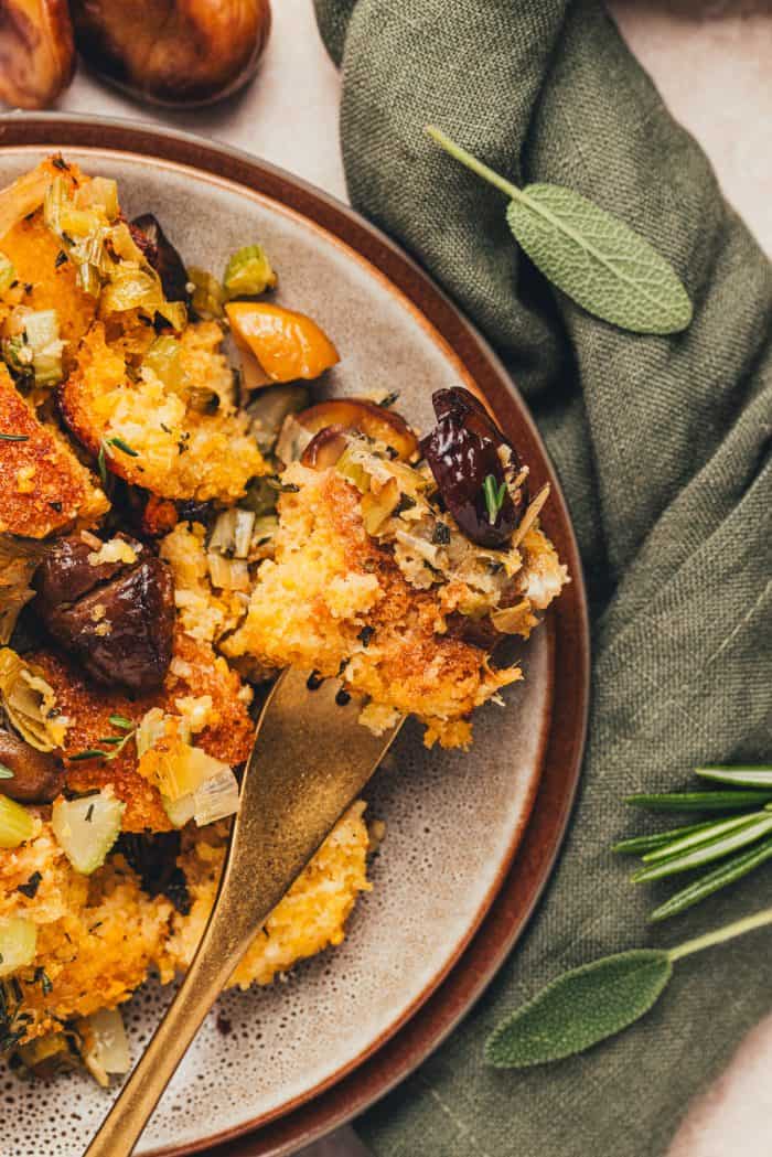 A fork being placed into a small plate of cornbread stuffing.