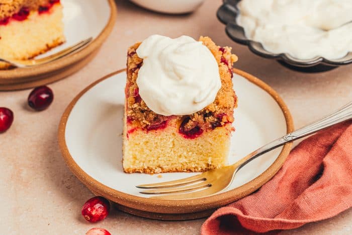 A slice of cranberry crumb cake on a small dessert plate with a fork.