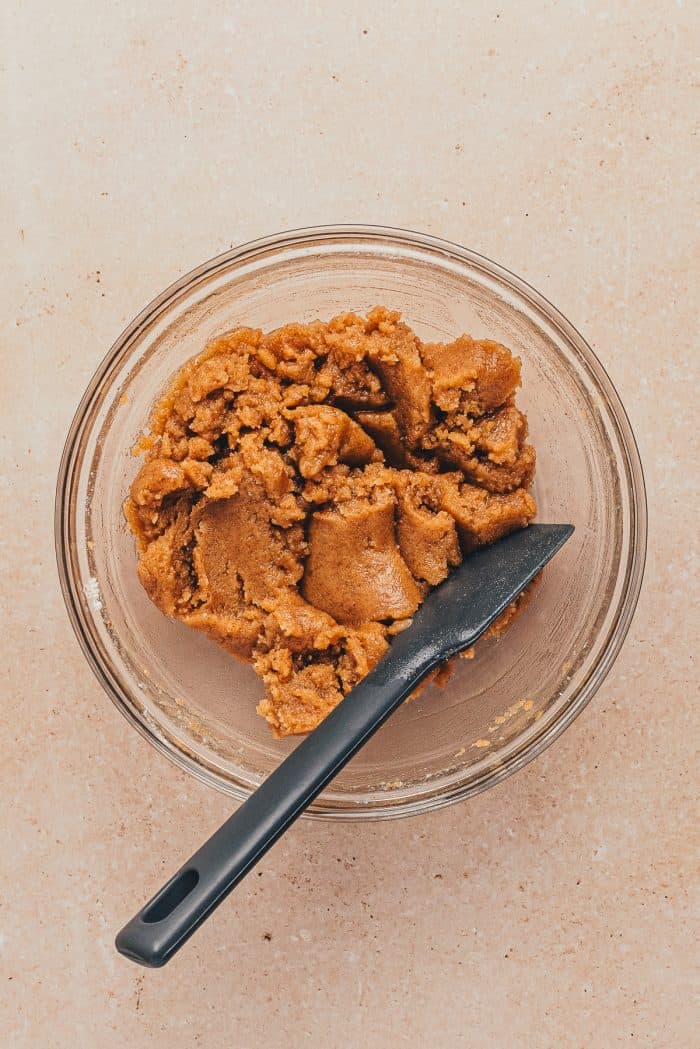 A glass bowl with the crumb mixture and a spatula.