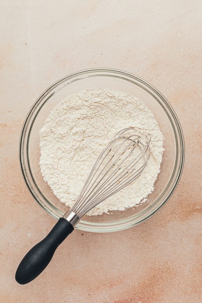 A mixing bowl with the flour mixture in it and a whisk.