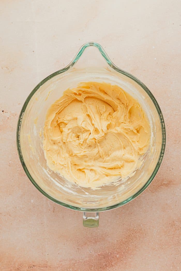 A glass mixing bowl with the butter, creamed in it.