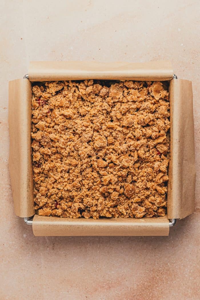 A square cake pan with the unbaked crumb cake.
