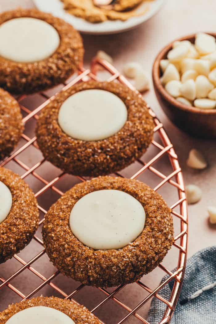 A variety of gingerbread thumbprint cookies on a cooling rack.