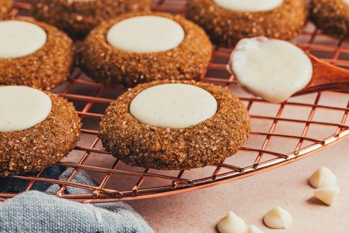 A variety of gingerbread thumbprint cookies on a cooling rack.
