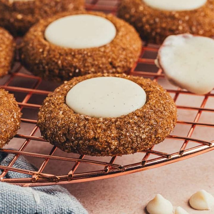 A variety of gingerbread thumbprint cookies on a cooling rack.