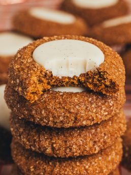 A stack of gingerbread thumbprint cookies with a bite taken out of one.