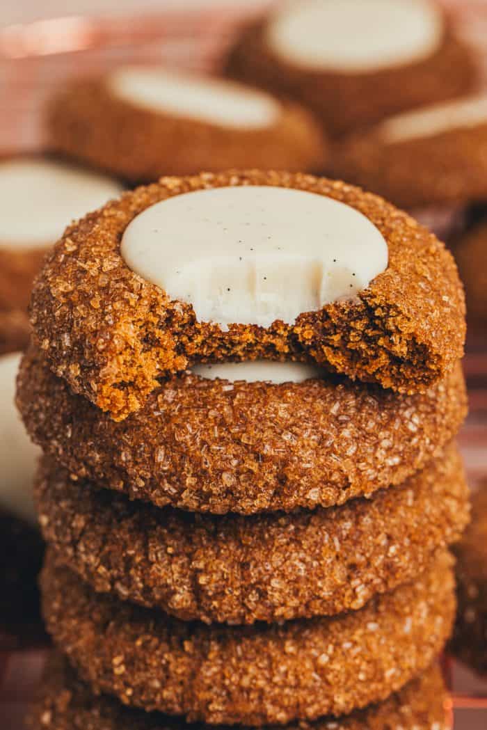 A stack of gingerbread thumbprint cookies with a bite taken out of one.