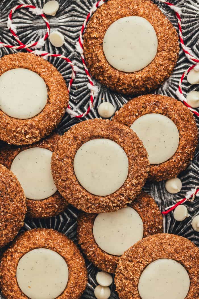 A platter with a variety of gingerbread thumbprint cookies and red and white string.