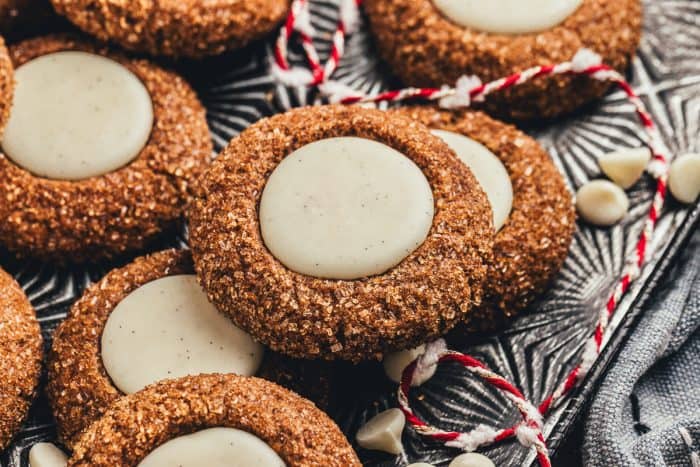 A platter with a variety of gingerbread thumbprint cookies and red and white string.