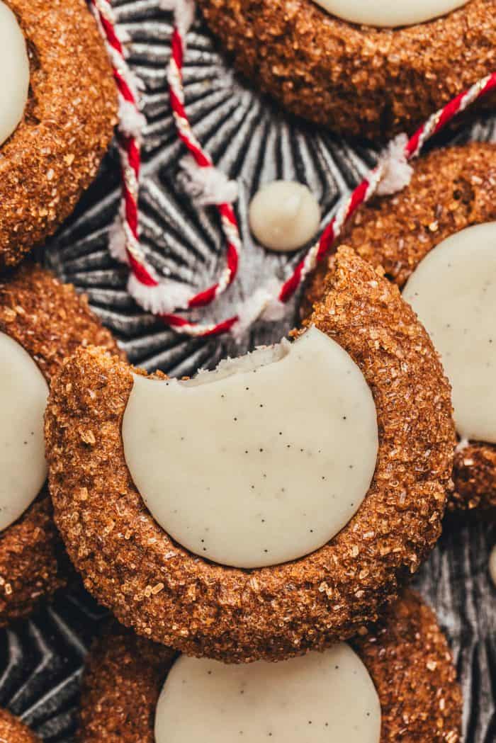 A platter with a variety of gingerbread thumbprint cookies, one has a bite taken out of it, and red and white string.