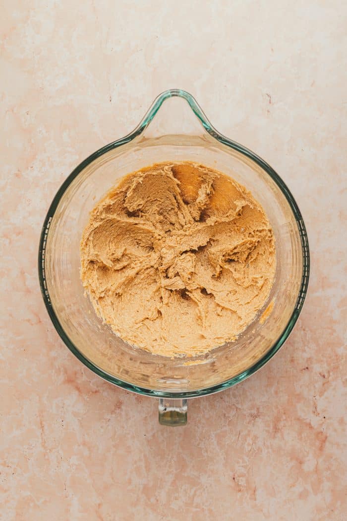 A glass mixing bowl with butter, brown sugar, and egg mixed together.