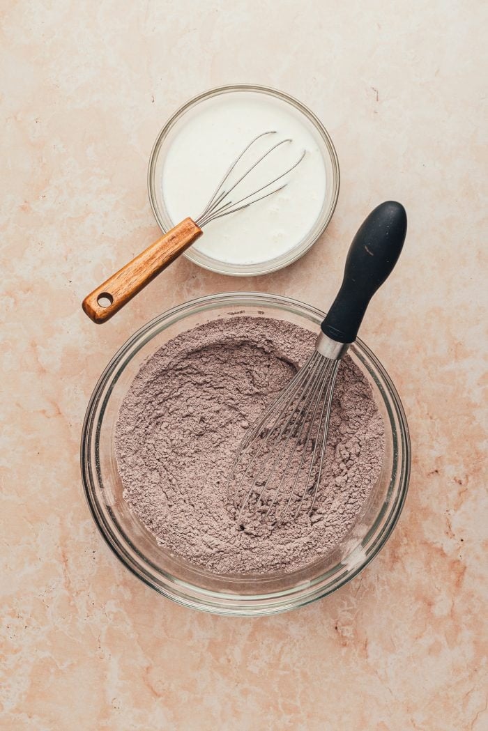 The dry ingredients added to a glass mixing bowl with a whisk.