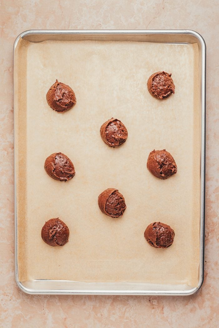 Spoonfuls of chocolate Whoopie pie batter on a baking sheet with parchment paper.