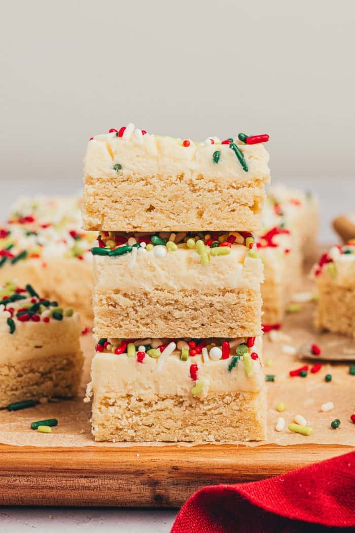 A stack of sugar cookie bars on a wooden cutting board.