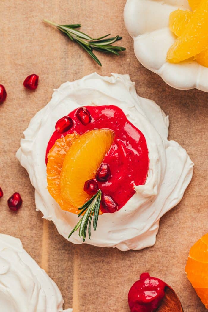 A mini pavlova with cranberry curd and orange slices with other garnishes.