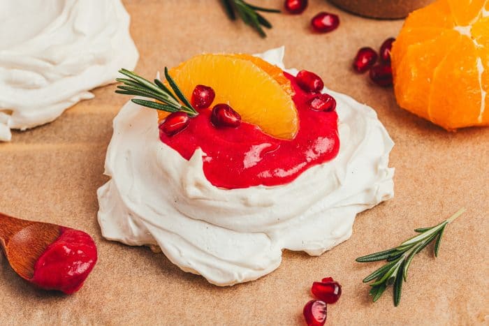 A mini pavlova with cranberry curd and orange slices with other garnishes.