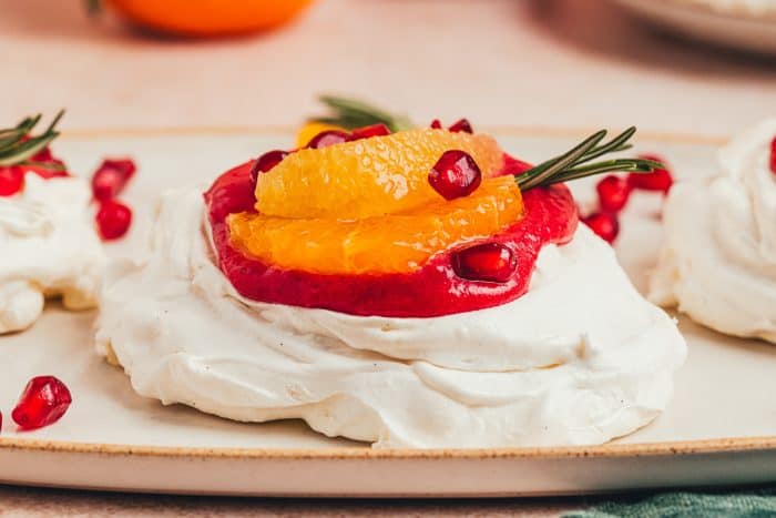 A mini pavlova with cranberry curd and orange slices with other garnishes.