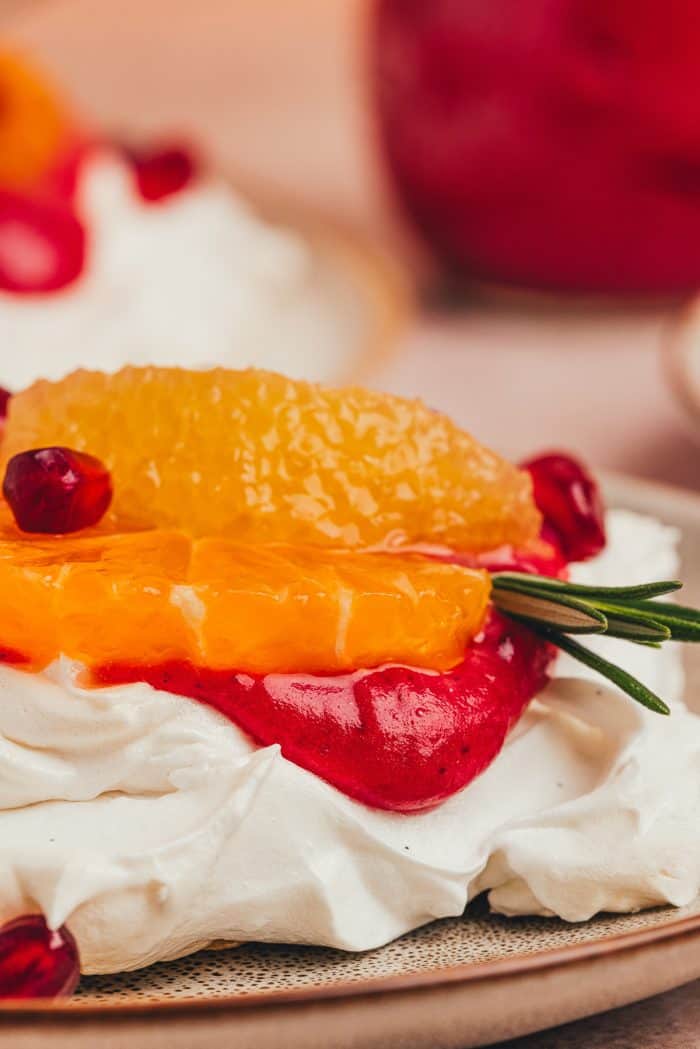 A mini pavlova with cranberry curd and orange slices with other garnishes.