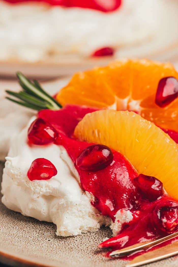 A mini pavlova with cranberry curd and orange slices with other garnishes.