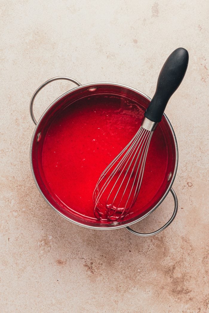 Blended cranberry sauce in a saucepan with a whisk.