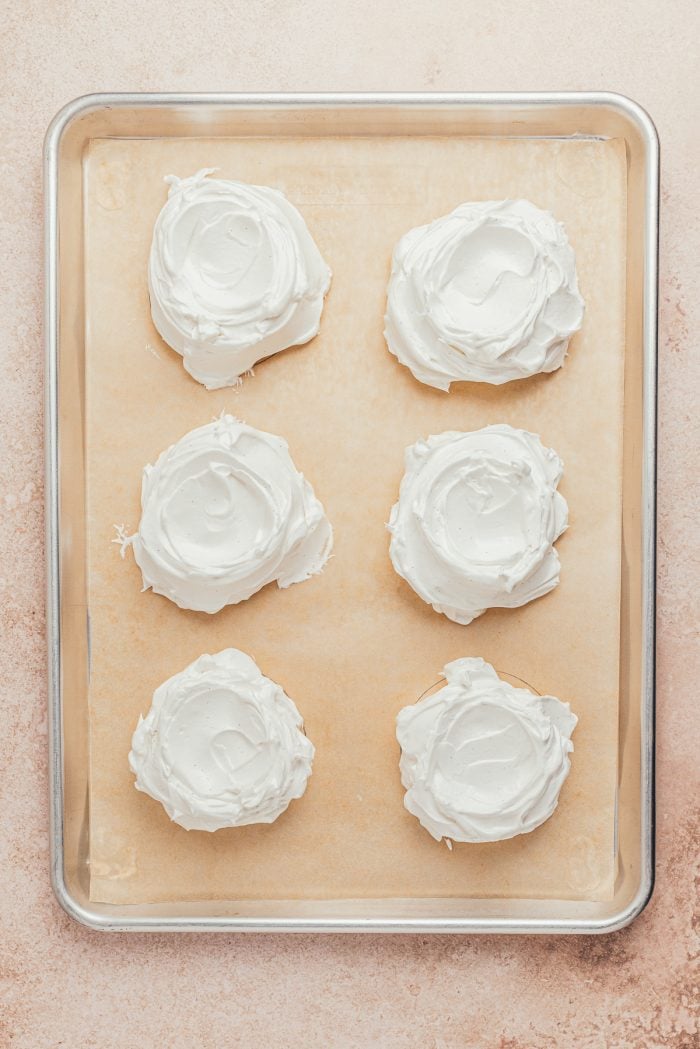 Unbaked Pavlovas on a baking sheet with parchment paper.