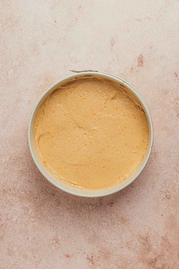 A round cake pan with cake batter in it.