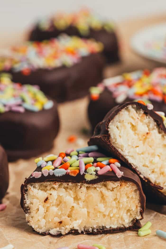 A few homemade chocolate Easter eggs scattered on parchment paper and one egg is split in half.
