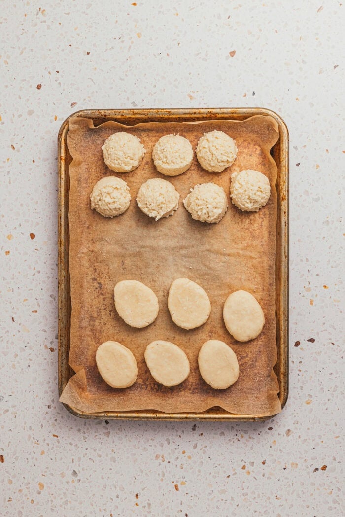 A mixture of the filling in a ball shape and some are in an egg shape on a tray with parchment paper.