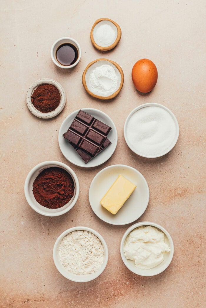 The ingredients to make a chocolate ricotta cake in various bowls.