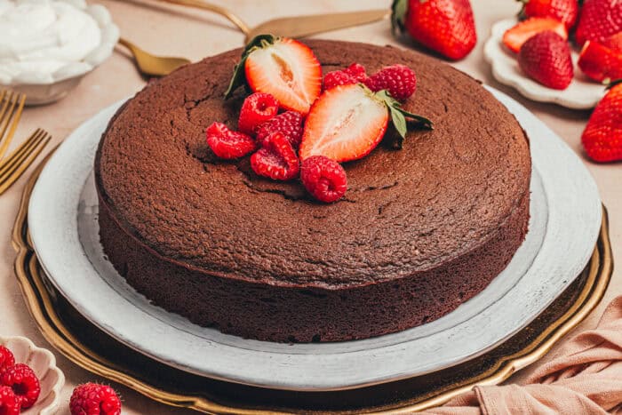 The baked chocolate ricotta cake on a platter with fresh fruit.